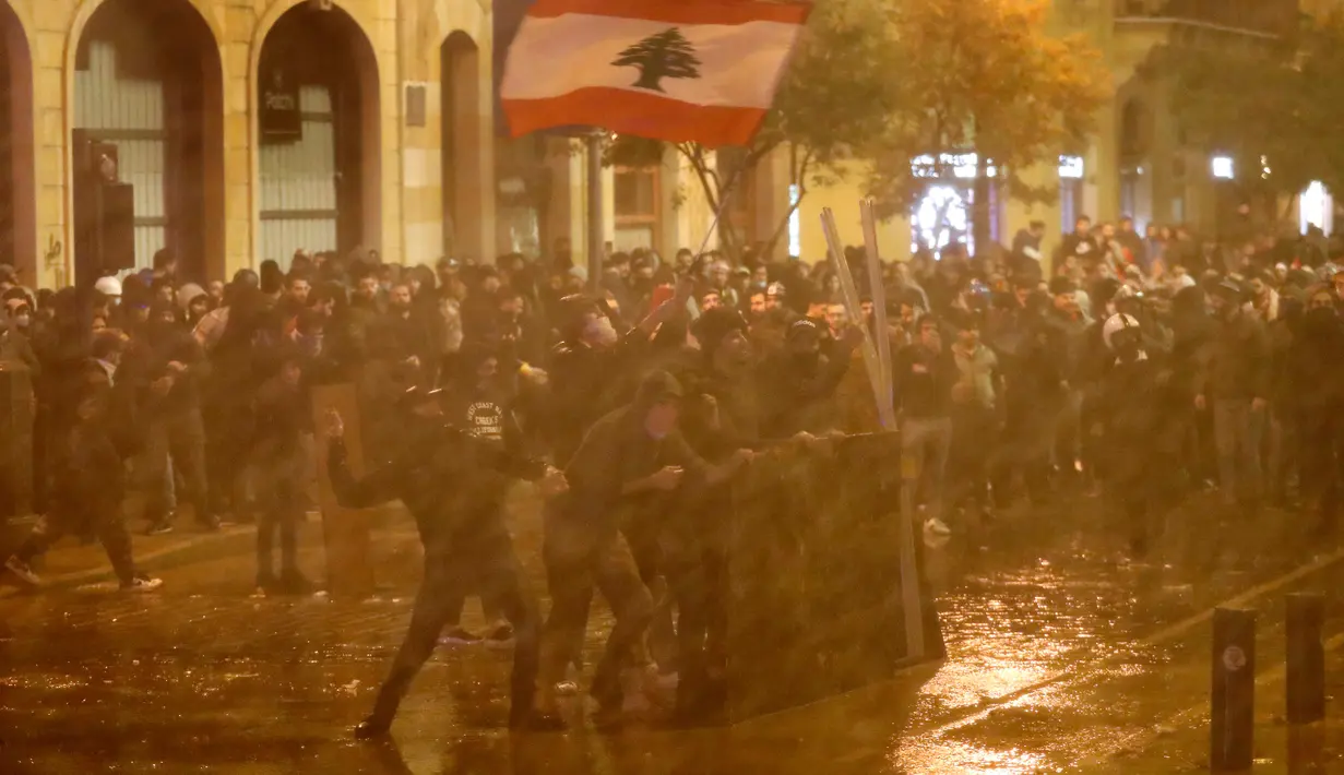 Demonstran antipemerintah disemprot air saat bentrok dengan polisi antihuru-hara dalam demonstrasi menentang pemerintahan baru dekat Parliament Square, Beirut, Lebanon, Rabu (22/1/2020). Demonstrasi dan kekerasan terus berlanjut kendati Lebanon telah mengumumkan kabinet baru. (AP Photo/HusseinMalla)
