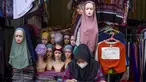 Seorang pedagang menggunakan telepon seluler pintarnya sambil menunggu pelanggan di sebuah kios pinggir jalan di Jakarta pada 30 Juni 2025. (BAY ISMOYO/AFP)