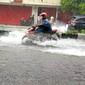 Seorang pengendara motor melintas di Jalan Basuki Rahmat Kota Malang yang tergenang air saat hujan lebat mengguyur (Liputan6.com/Zainul Arifin(
