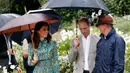 Pangeran William (tengah) dan Kate Middleton (kiri) dipandu saat berkeliling  di taman Istana Kensington, London, Rabu (30/8). Kate mengenakan gaun yang sesuai dengan acara ini, karena bunga Poppy memiliki simbol “mengingat”. (Kirsty Wigglesworth/AP)