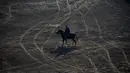 Seorang penunggang kuda bersiap untuk mengikuti pertandingan olahraga tradisional Buzkashi di Mazar-i-Sharif, Afghanistan (20/12). Olahraga ini dimainkan antara dua tim yang bersaing untuk membawa bangkai hewan ke lingkaran. (AFP/Farshad Usyan)