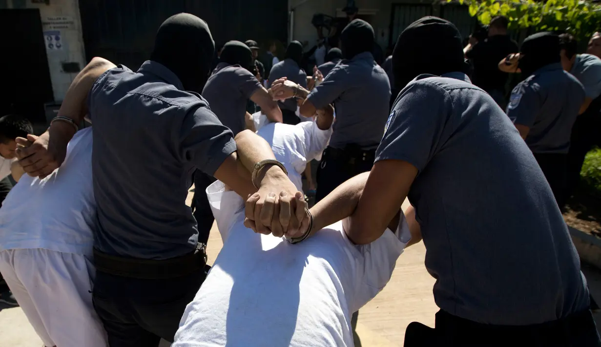 Petugas kepolisian menggelandang anggota geng Mara Salvatrucha di Zacatecoluca, El Salvador (31/1). Mara Salvatrucha merupakan geng kriminal yang berasal dari Los Angeles, AS yang telah menyebar ke Amerika Tengah dan Kanada. (AP Photo/Moises Castillo)