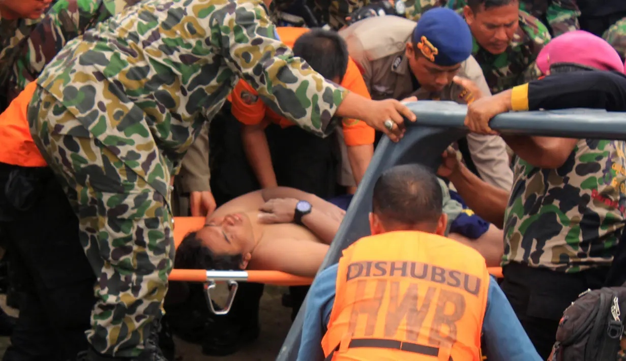 Tim SAR membawa penumpang korban helikopter jatuh yang selamat, Fransiskus Subihardayan (tengah) usai ditemukan mengapung di Danau Toba, Sumatera, Selasa (13/10). Pria itu mengapung setelah dua hari helikopter EC 130 hilang kontak. (AFP PHOTO)