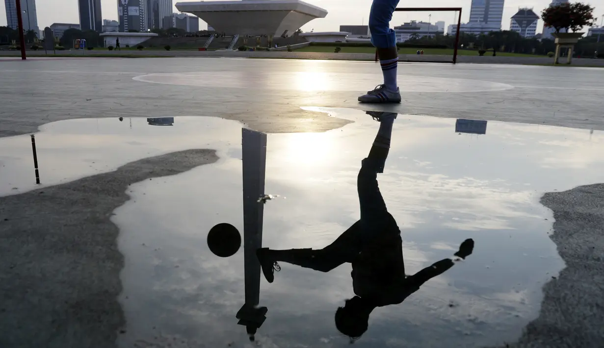 Seorang warga mengontrol bola saat olahraga sepak bola di Kawasan Monumen Nasional, Jakarta, Rabu (13/2). Monas merupakan salah satu lokasi yang kerap dijadikan ruang olahraga bagi warga ibukota. (Bola.com/M. Iqbal Ichsan)