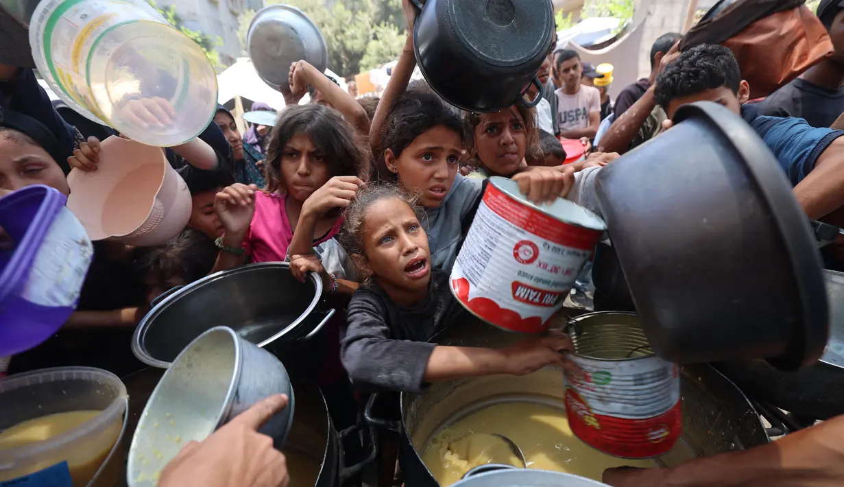 Anak-anak Palestina mengantre untuk menerima makanan hangat di sebuah titik distribusi makanan di Nuseirat pada 30 Juni 2025. (Eyad BABA/AFP)