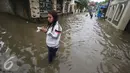 Warga melintasi banjir yang menggenangi Jalan Ketapang di kawasan Pasar Minggu, Jakarta, Selasa (4/10). Banjir yang berasal dari luapan Kali Anur tersebut menyebabkan Jalan Ketapang tidak bisa dilewati kendaraan. (Liputan6.com/Immanuel Antonius)