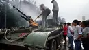 4 Juni 1989, beberapa warga memeriksa kendaraan lapis baja yang terbakar di dekat Lapangan Tiananmen, Tiongkok. (AFP PHOTO/TOMMY CHENG)