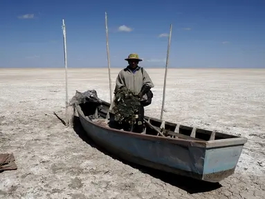 Seorang nelayan dari kelompok etnik Urus berdiri di atas perahunya yang tergeletak di Danau Poopo, La Paz, Bolivia, (17/12). Banyak nelayan kehilangan pekerjaannya akibat keringnya danau ini. (REUTERS/David Mercado)
