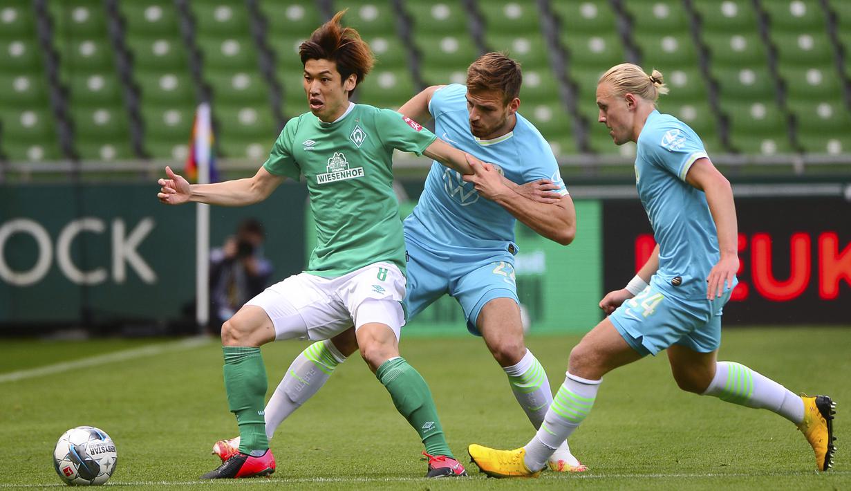 Pemain Werder Bremen, Yuya Osako, berebut bola dengan pemain Wolfsburg, Marin Pongracic, pada laga Bundesliga di Weserstadion Minggu (7/6/2020). Werder Bremen takluk 0-1 dari Wolfsburg. (AFP/Patrik Stollarz)