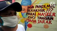 Warga berjalan melintasi mural bertema COVID-19 di kawasan Tanah Tinggi, Tangerang, Banten, Rabu (20/1/2020). Kegiatan ini dalam rangka mensosialisasikan bahaya penyebaran COVID-19 kepada warga pengguna jalan umum. (merdeka.com/Arie Basuki)