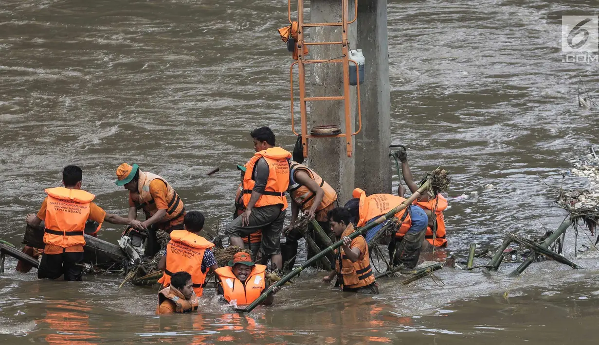 Sejumlah pasukan oranye berjibaku membersihkan sampah batang kayu dan bambu yang tersangkut di aliran sungai Ciliwung di kawasan Sudirman, Jakarta, Jumat (9/2). (Liputan6.com/Faizal Fanani)