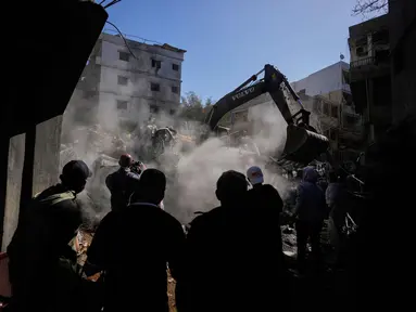 Orang-orang berkumpul saat sebuah ekskavator membersihkan puing-puing di lokasi serangan Israel pada Minggu 5 April 2026 terhadap sebuah bangunan di lingkungan Jnah, Beirut, Lebanon, Senin 6 April 2026. (AP Photo/Hassan Ammar)