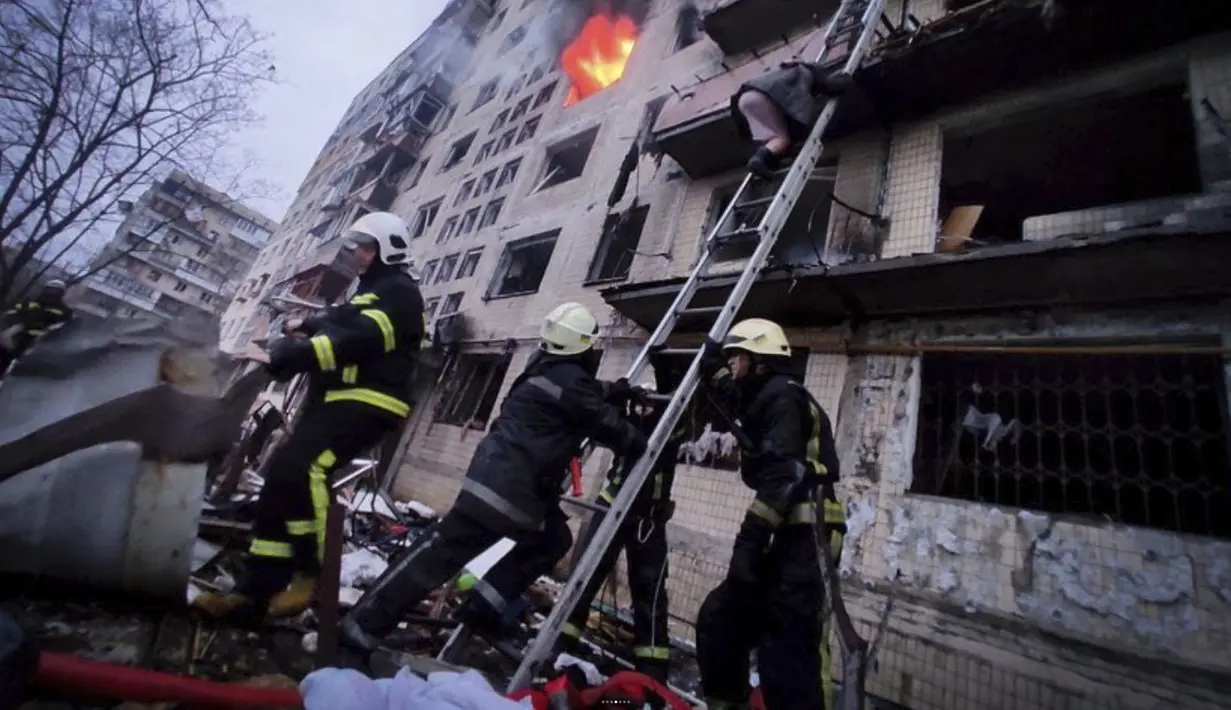Petugas pemadam kebakaran berusaha mengevakuasi warga dari gedung apartemen yang terkena tembakan di Kyiv, Ukraina (14/3/2022). Dua orang tewas pada 14 Maret 2022 akibat serangan penembakan dan rudal Rusia yang menghancurkan gedung apartemen tersebut. (Ukrainian State Emergency Service via AP)