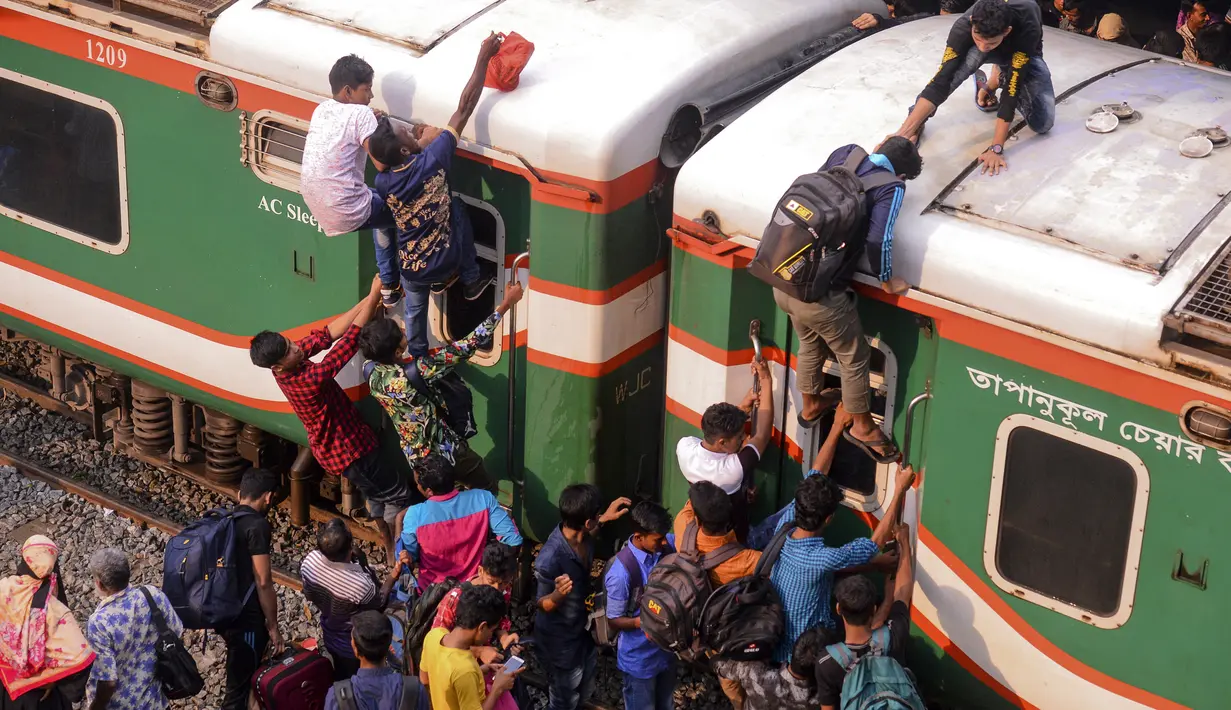 Ratusan orang berupaya menaiki atap kereta api untuk menuju kampung halaman di Dhaka, Bangladesh pada 4 Juni 2019. Pemadangan mencengangkan dari ratusan yang naik dan duduk di atas kereta karena gerbong yang penuh terlihat pada menjelang Idul Fitri di Bangladesh. (MUNIR UZ ZAMAN/AFP)