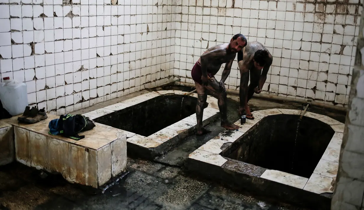 Pengunjung melumuri tubuhnya menggunakan lumpur dari sumber belerang guna menyehatkan kulit mereka di Hamam Alli, Mosul, Irak, (27/4). (AP Photo/Bram Janssen)