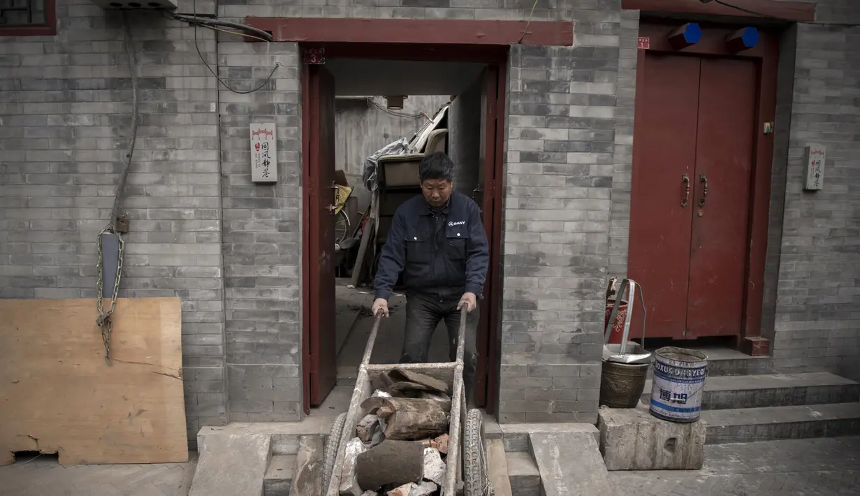 Seorang pekerja mendorong gerobak dorong keluar dari sebuah rumah yang sedang diperbarui di daerah hutong di Beijing (26/2). (AFP Photo/Nicolas Asfouri)