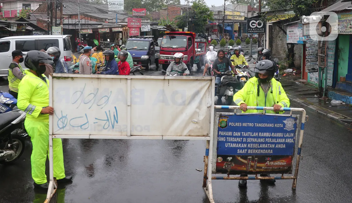 Petugas kepolisian melakukan penutupan jalan KH Hasyim Ashari, Kota Tangerang, Banten, Sabtu (16/7/2022). Intensitas curah hujan yang tinggi sejak Jumat (15/7) siang menyebabkan akses jalan Hasyim Ashari terputus karena terendam banjir setinggi 50 hingga 70 sentimeter. (Liputan6.com/Angga Yuniar)