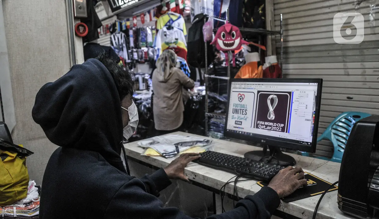 Pekerja mendesain logo Piala Dunia 2022 di salah satu kios Blok B Pasar Tanah Abang, Jakarta Pusat, Kamis (8/12/2022). Selain Jakarta, permintaan jasa sablon jersey bertema Piala Dunia 2022 banyak dipesan dari luar Jawa hingga Papua. (merdeka.com/Iqbal S. Nugroho)