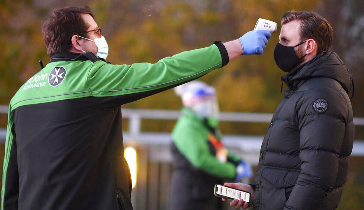 SUPORTER DIUKUR SUHU TUBUHNYA: Petugas memeriksa suhu tubuh suporter West Ham United sebelum menyaksikan pertandingan melawan Manchester United di Stadion London, Sabtu (5/12/2020). (Justin Setterfield/Pool Via AP)