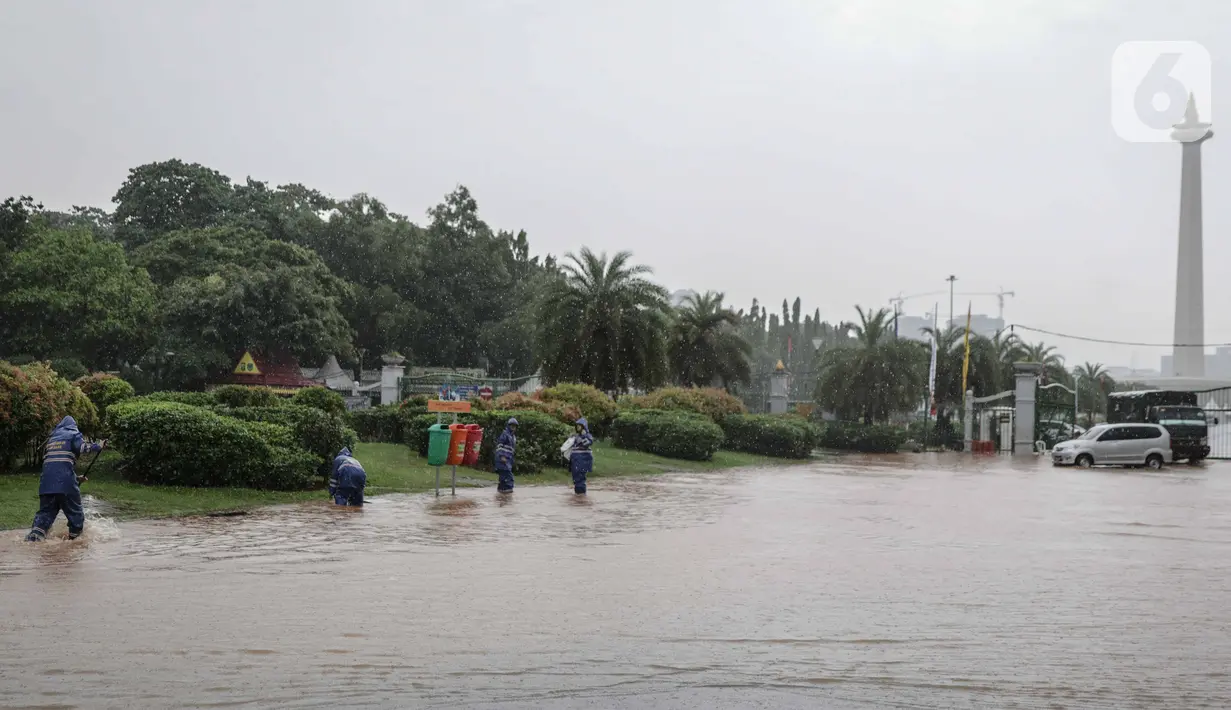 Petugas mengecek genangan air di Jalan Medan Merdeka Barat, Jakarta, Kamis (24/1/2020). Hujan deras yang mengguyur Jakarta sejak pagi tadi mengakibatkan genangan air di Jalan Medan Merdeka Barat. (Liputan6.com/Faizal Fanani)