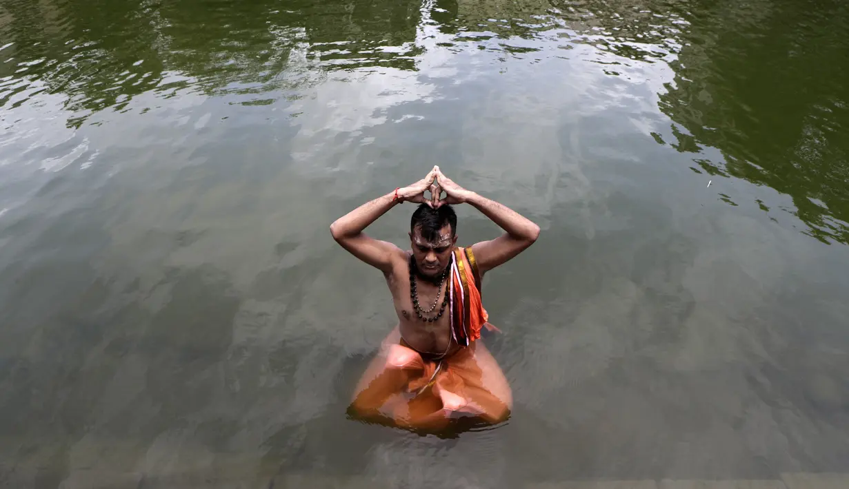 Umat Hindu duduk dalam kolam saat melakukan ritual selama gerhana matahari di Banganga, Mumbai, India, Minggu (21/6/2020). Fenomena gerhana matahari pada 21 Juni 2020 terlihat dari berbagai negara di dunia. (AP Photo/Rajanish Kakade)