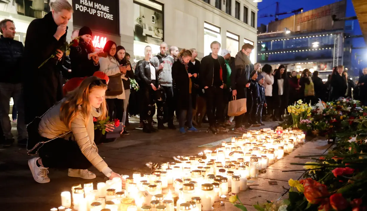 Lilin dan bunga diletakkan warga di lokasi terjadinya serangan truk sebagai bentuk ungkapan berkabung di Stockholm, Swedia, Minggu (9/4). Sebuah truk yang dibajak menabrakkan diri ke kerumunan pejalan kaki pada Sabtu (8/4). (AP Photo / Markus Schreiber)