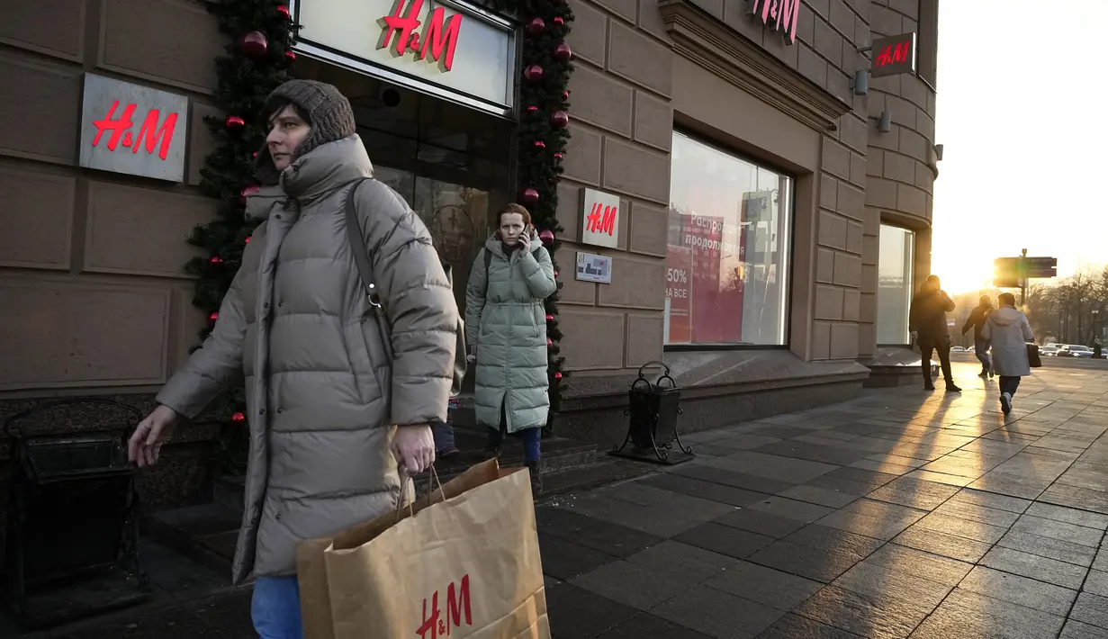 Seorang perempuan membawa kantong belanja setelah meninggalkan toko utama H&M di Moskow, Rusia, Rabu (30/11/2022). Pengecer mode no.2 dunia itu akhirnya menutup semua tokonya di Rusia untuk selamanya. (AP Photo/Alexander Zemlianichenko)