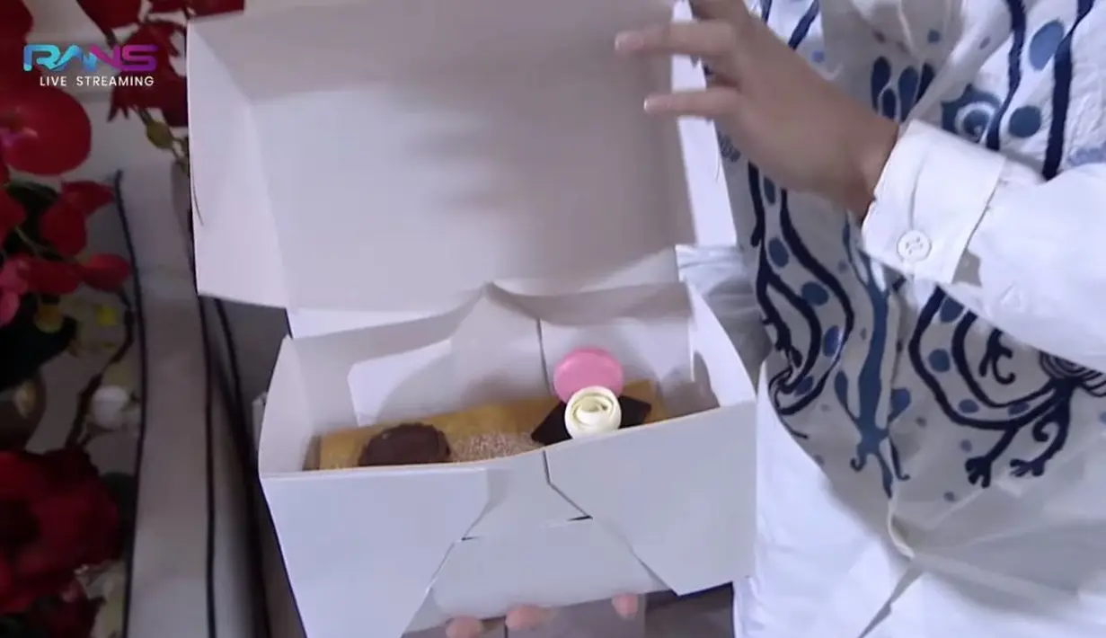 Jirayut membuka kotak kedua yang agak besar. Di kotak itu terdapat sebuah kue yang berhias macaroon di atasnya. (Sumber: YouTube/ Rans Entertainment)