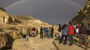 Pelangi terlihat saat warga Israel melihat banjir bandang yang terjadi menyusul hujan lebat di gurun Negev di sebelah timur kota Dimona Israel pada 26 Desember 2022. Hujan deras mengguyur Israel utara, dataran pantai, Yerusalem, dan sebagian Negev utara, termasuk kilat dan angin kencang di beberapa daerah. (AFP/Menahem Kahana)