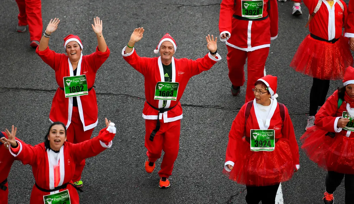 Peserta berkostum Sinterklas melambaikan tangan saat mengikuti Santa Claus Run di Madrid, Spanyol, Minggu (9/12). Ribuan orang berjalan dan berlari dalam perlombaan Santa tahunan melintasi jalan-jalan ibu kota Spanyol. (Gabriel BOUYS / AFP)