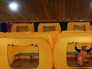 Petugas merapihkan tenda yang akan dijadikan tempat isolasi Covid-19 di gedung kesenian Tanah Abang, Jakarta, Minggu (17/5/2020). Gedung ini dijadikan tempat isolasi bagi masyarakat yang  akan mengikuti rapid test esok dilokasi tersebut. (Liputan6.com/Angga Yuniar)
