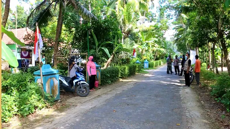 Warga memasang bendera merah putih di depan rumah keluarga yang menjalani isolasi mandiri untuk memberi semangat. (Foto: Liputan6.com/Polres Kebumen)