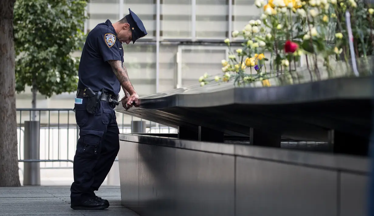 Petugas NYPD tertunduk saat menghadiri upacara peringatan 16 tahun korban serangan 11 September di Museum dan Memorial Nasional 9/11, New York, Amerika Serikat, Senin (11/9). (Drew Angerer/Getty Images/AFP)
