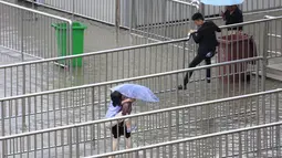 Sejumlah orang berjalan di atas pagar untuk mencoba menyebrang jalan yang terkena banjir, Shanghai, Tiongkok, Senin (24/8/2015). Banjir disebabkan oleh hujan deras yang menimpa kawasan tersebut. (Reuters/Aly Lagu)