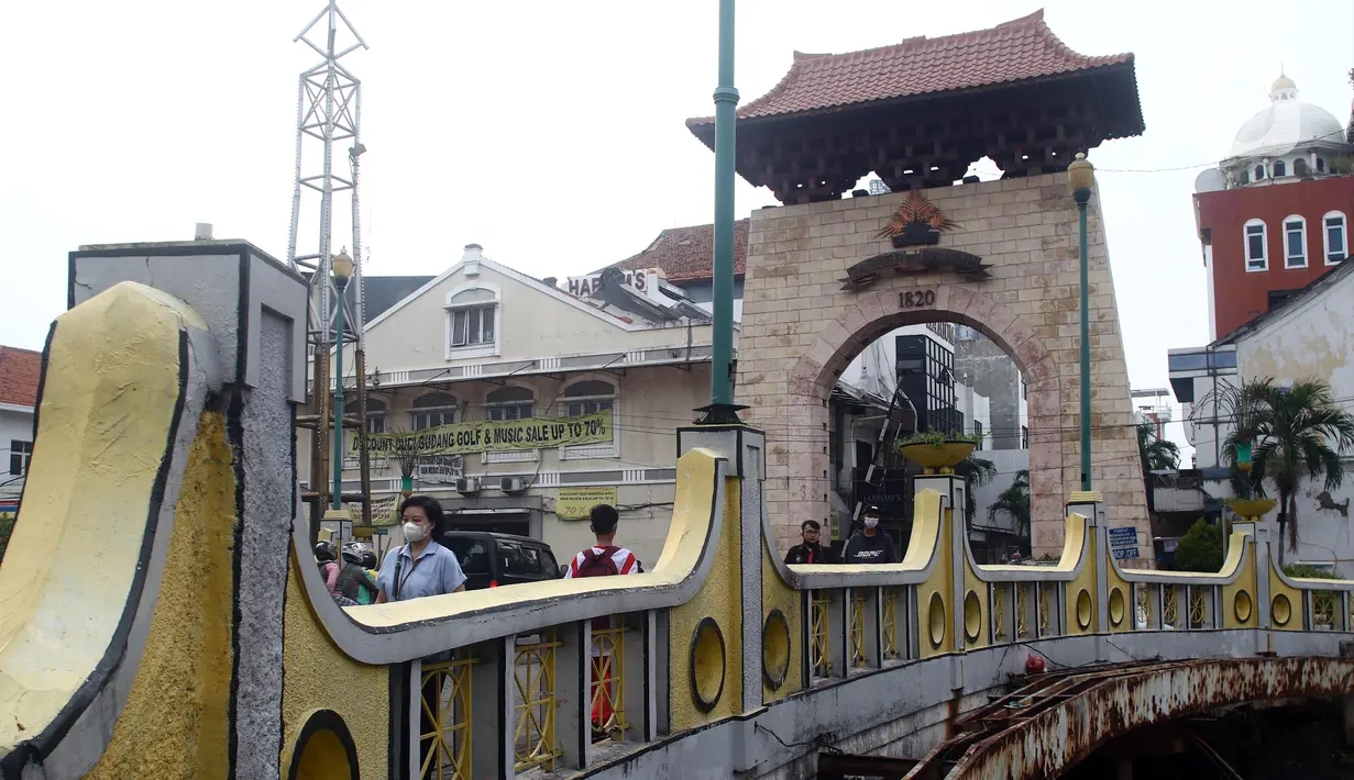 Warga berjalan di jembatan penghubung depan gerbang kawasan Pasar Baru, Jakarta, Kamis (22/9/2022). Penetapan Kompleks Jalan Pasar Baru sebagai Kawasan Cagar Budaya pada Rabu (21/9/2022) dilakukan setelah proses kajian yang dilakukan oleh Tim Ahli Cagar Budaya (TACB) Provinsi DKI Jakarta serta ditetapkan melalui Keputusan Gubernur. (Liputan6.com/Helmi Fithriansyah)