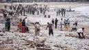 Para pekerja dan warga membersihkan ceceran dan tumpukan sampah plastik yang terdampar di Pantai Jimbaran, Bali, pada Selasa 10 Maret 2026. Pantai Jimbaran, Bali, kembali dipenuhi sampah kiriman. (Lana Priatna/AFP)