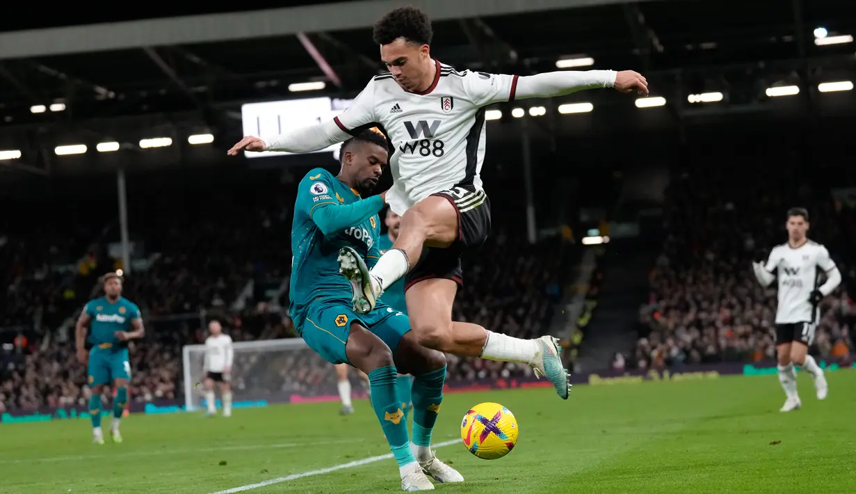 Pemain Wolverhampton Wanderers Nelson Semedo (kiri) memperebutkan bola dengan pemain Fulham Antonee Robinson pada pertandingan sepak bola Liga Inggris di Stadion Craven Cottage, London, Inggris, 24 Februari 2023. Pertandingan berakhir imbang 1-1. (AP Photo/Kirsty Wigglesworth)