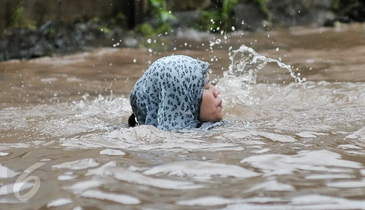 Seorang wanita terjatuh ke dalam lubang yang tak terlihat saat melintasi banjir di Jalan Taman Bukit Duri, Jakarta Selatan, Selasa (21/2). (Liputan6.com/Yoppy Renato)