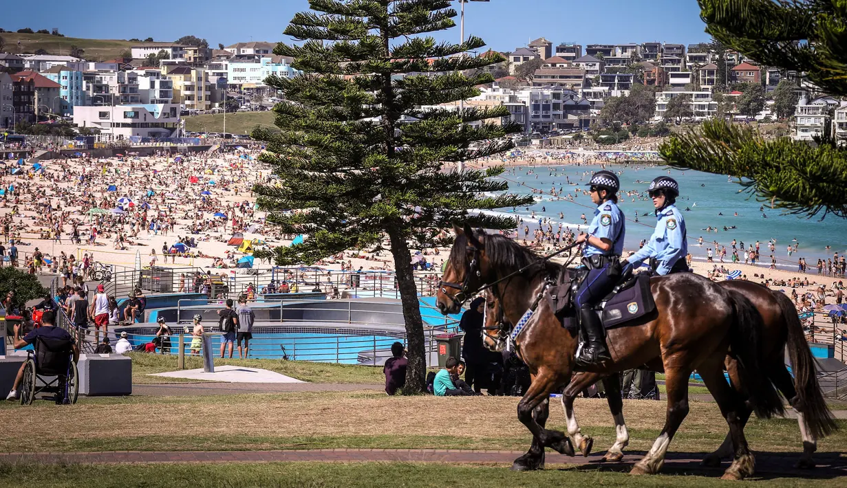 Polisi berkuda berpatroli saat mengunjungi pantai Bondi di Sydney, Australia pada 5 Oktober 2020. Kerumunan warga dan aktivitas yang ramai ini membuat penerapan jarak sosial menjadi nyaris mustahil dilakukan.  (Photo by DAVID GRAY / AFP)