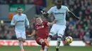 Kapten Liverpool, James Milner (kiri) menghalau bola dari kaki pemain West Ham, Cheikhou Kouyate pada laga Premier League pekan ke-28 di Anfield Stadium, Liverpool, (24/2/2018). Liverpool menang 4-1. (AFP/Oli Scarff)