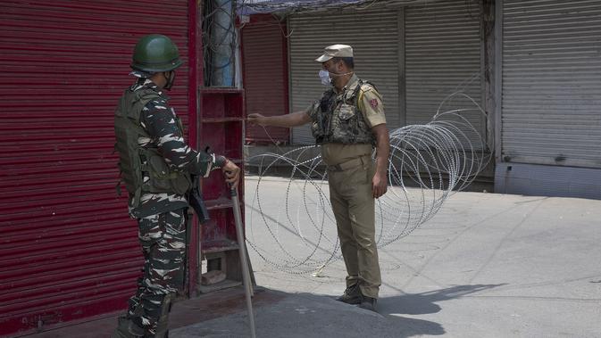 Seorang polisi India (kanan) memblokade sebuah jalan saat penerapan karantina wilayah (lockdown) guna membendung penyebaran pandemi COVID-19 di Kota Srinagar, ibu kota musim panas Kashmir yang dikuasai India (26/7/2020). (Xinhua/Javed Dar)