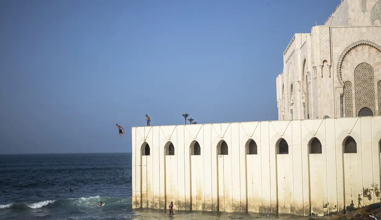 Seorang pria melompat untuk menyelam ke Samudra Atlantik dari dinding masjid Hassan II di Casablanca, Maroko (7/2/2020). Masjid ini memiliki minaret yang paling tinggi di dunia dengan ketinggian 210 meter (689 kaki) dan memiliki kapasitas 25.000 orang. (AP Photo/Mosaab Elshamy)
