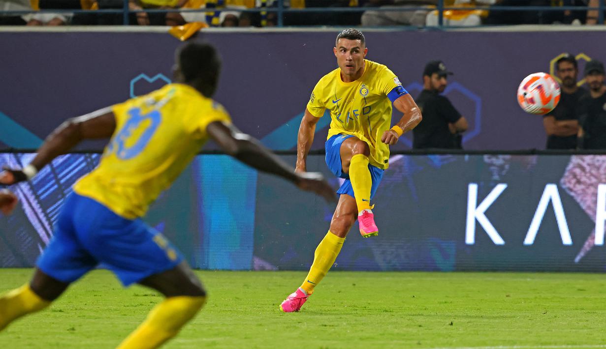 Pemain Al Nassr, Cristiano Ronaldo (kanan), menendang bola ke gawang Al Taawon dalam laga pekan ke-2 Liga Arab Saudi 2023/2024 yang berlangsung di KSU Football Stadium, Sabtu (19/8/2023) dini hari WIB. Al Nassr mencatatkan percobaan tembakan dibabak pertama, tapi hanya dua yang tepat sasaran. (AFP/Fayez Nureldine)