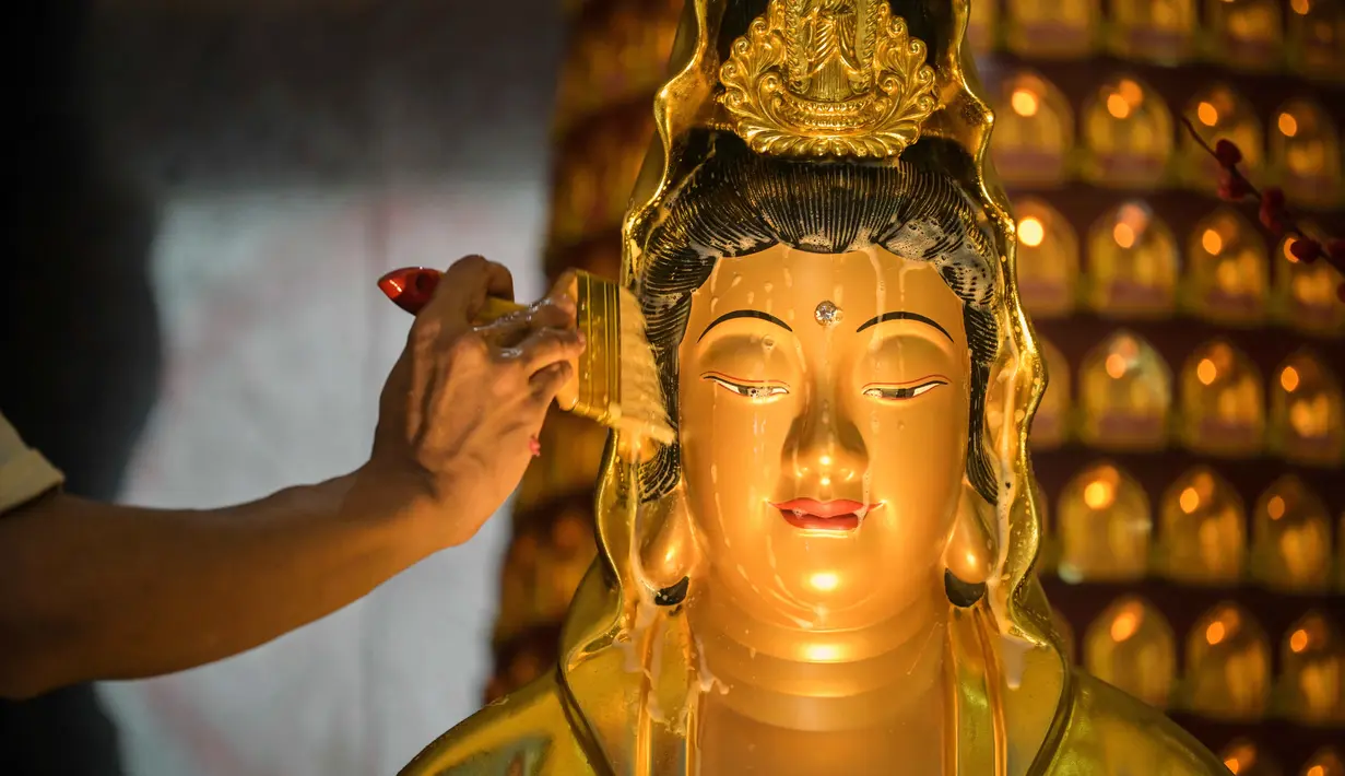 Pembersihan dimulai dari area wajah, kemudian dilanjutkan ke bagian tangan hingga kaki, dilakukan dengan penuh kehati-hatian dan kekhusyukan. Tampak dalam foto, seorang pria membersihkan patung Buddha sebagai persiapan perayaan Tahun Baru Imlek 2577 Kongzili di Vihara Buddhayana, Surabaya, Jawa Timur pada Senin 9 Februari 2026. (JUNI KRISWANTO/AFP)