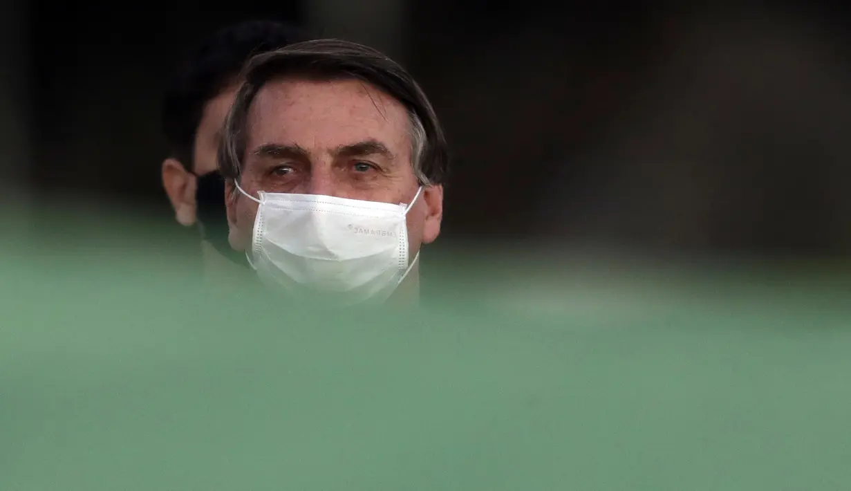 Presiden Brasil Jair Bolsonaro mengenakan masker saat upacara retret bendera di luar Istana Alvorada, Brasilia, Brasil, Jumat (24/7/2020). Jair Bolsonaro dinyatakan positif terinfeksi COVID-19 pada 7 Juli lalu. (AP Photo/Eraldo Peres)
