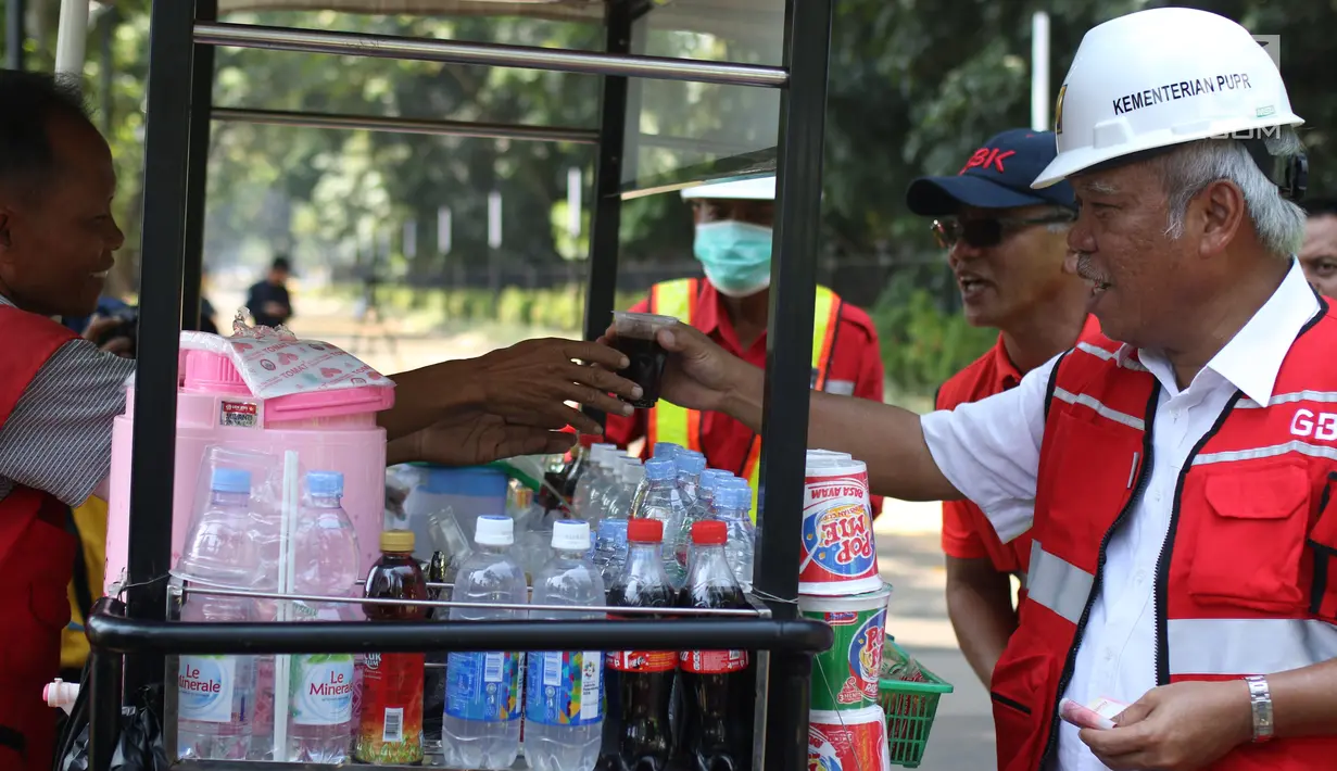 Menteri PUPR, Basuki Hadimuljono membeli kopi yang dijajakan pedagang seusai meninjau renovasi stadion di Gelora Bung Karno (GBK), Jakarta, Kamis (10/5). Basuki meninjau kesiapan fasilitas dan prasarana untuk Asian Games 2018. (Liputan6.com/Angga Yuniar)