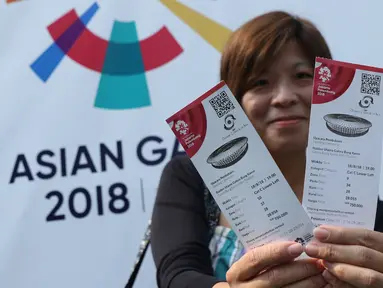 Salah satu calon penonton seremoni pembukaan Asian Games 2018 menunjukkan tiketnya jelang masuk kawasan GBK, Jakarta, Sabtu (18/8). Asian Games 2018 akan berlangsung hingga 2 September, mendatang. (Liputan6.com/Helmi Fithriansyah)