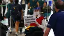 Seorang wanita mengenakan masker dan pelindung wajah menyambut kedatangan pemain timnas softball Australia di Bandara internasional Narita, Jepang, Selasa (1/6/2021). Timnas softball Australia termasuk di antara yang paling awal datang untuk Olimpiade Tokyo. (Issei Kato/Pool Photo via AP)