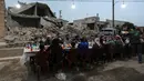 Warga Suriah berkumpul di daerah yang rusak berat untuk berbuka puasa di Tadef, dekat kota perbatasan al-Bab, yang dikendalikan pemberontak yang didukung Turki di Suriah (18/4/2022). Buka puasa ini diselenggarakan oleh sebuah LSM berkoordinasi dengan berbagai faksi lokal. (AFP/Bakr Alkasem)