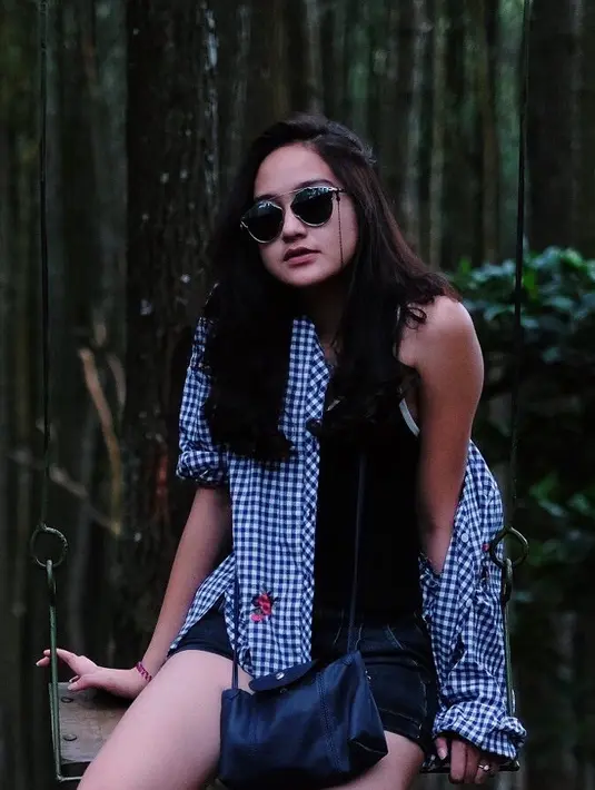 Berada di kawasan hutan dengan pepohonan yang besar-besar,  Salshabilla tampil kece dengan sunglasessnya. Terlebih dengan rambutnya yang terurai dan gaya baju bermoif kotak-kotak kecilnya itu. (Instagram/salshabillaadr)